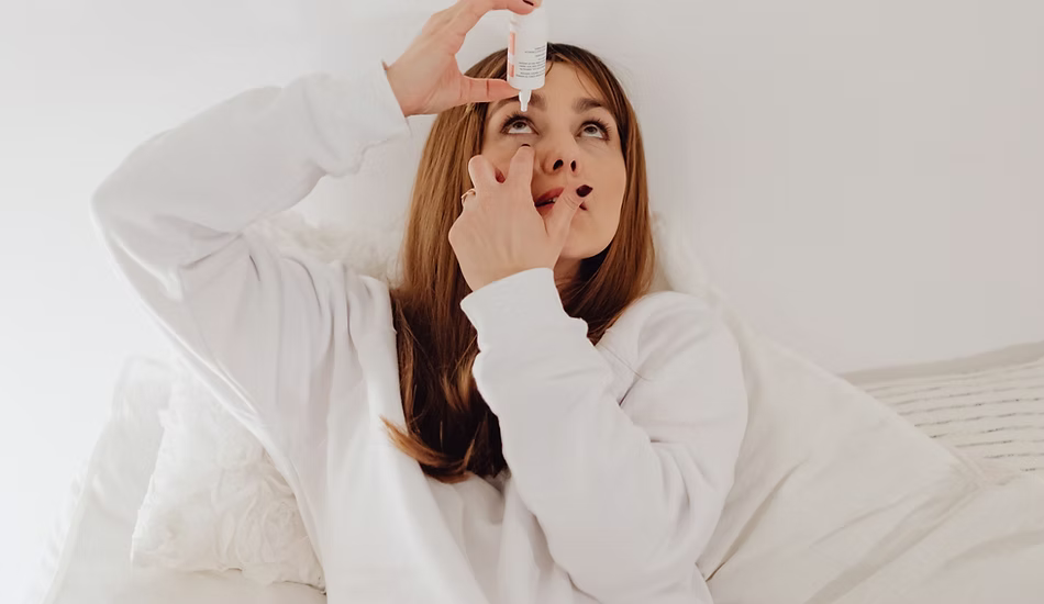 Femme qui se met des gouttes pour apaiser la sécheresse oculaire.